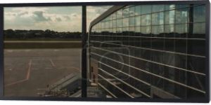 Panoramiczne ujęcie szklanej fasady lotniska z lotniskiem i zachmurzonym niebem w tle w Kopenhadze, Dania 