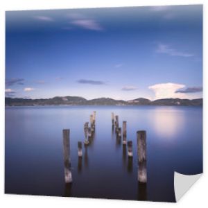 Drewniane molo lub molo pozostaje na niebieskim jeziorze o zachodzie słońca. Włochy