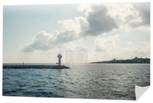 Latarnia morska na molo na morzu i zachmurzone niebo na tle Stambułu, Turcja 