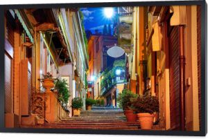 Bellagio wieś nad jeziorem Como niedaleko Mediolanu Włochy, region Lombardia. Słynna ulica ze schodami z kostki brukowej i przytulnymi restauracjami o wschodzie słońca ze świecącymi lampionami i zielonymi roślinami na ścianach starych domów.