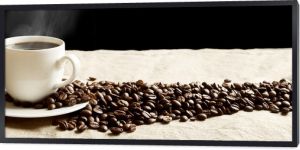 Panoramiczny widok spienionej filiżanki kawy z ziarnami na tkaninie lnianej