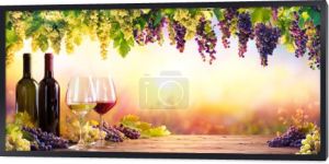 Butelki i kieliszki z winogron o zachodzie słońca