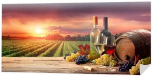 Beczki Wineglasses i butelka w winnicy o zachodzie słońca