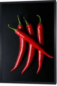 Cztery czerwone papryczki chili z czarnym tłem