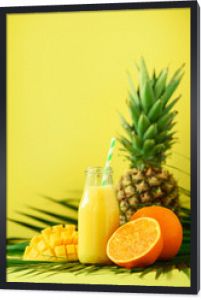 Pyszne soczyste smoothie z owocami pomarańczy, mango, ananasem na żółtym tle. Skopiuj miejsce. Projekt pop-artu, koncepcja kreatywnych lato. Świeży sok w szklanym słoju na zielonych liściach palmowych.