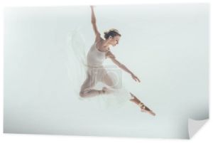 Piękna tancerka w białej sukni skoki w studio, na białym tle