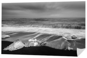 Kostka lodu z gładką falą na czarnej, piaszczystej plaży Islandia w odcieniu czerni i bieli