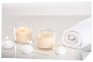 palenie białych świec w szkle i walcowany ręcznik na marmurowej białej powierzchni
