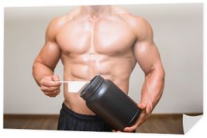 Kulturysta trzymający łyżkę mieszanki proteinowej na siłowni