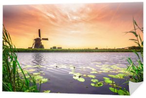 Tradycyjna wioska z holenderskimi wiatrakami i rzeką o zachodzie słońca, Holandia, Holandia.
