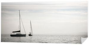 Jezioro Garda, Włochy. Para jachtów unoszących się łagodnie na spokojnych wodach Pojezierza Włoskiego.