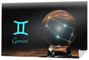 kryształowa kula z konstelacją w pobliżu znaku zodiaku Gemini na drewnianym stole odizolowana na czarno
