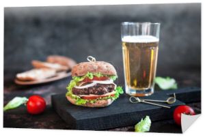 Duże smaczny hamburger z szkło kubek piwa światła na ciemnym tle drewnianych