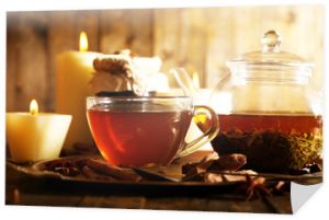 Kompozycja z herbatą w filiżance i czajniczku i świecami