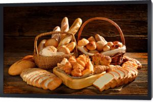 Różnorodność chleba w wiklinowym koszu na stare drewniane tła.