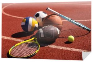 Różnorodny sprzęt sportowy, w tym amerykański futbol, piłka nożna, rakieta tenisowa, piłka tenisowa i koszykówka.