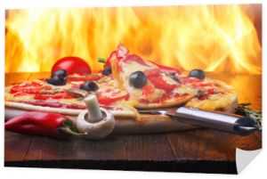 Pizza na drewnianym stole z prawdziwym ogniem piekarnika na tle