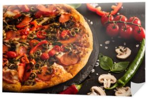 pyszne włoskie pizzy z salami w pobliżu warzyw na czarnym tle