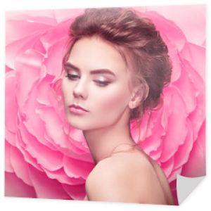 Piękna kobieta na tle dużego kwiatu. Piękna dziewczyna model lato z różową piwonią. Młoda kobieta z elegancką fryzurą i makijażem. Fotografia mody