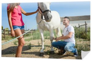 przystojny młody mężczyzna weterynarz opiekujący się pięknym biało-szarym koniem camargue