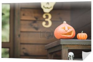 rzeźbiona dynia i upiorna czaszka na ganku drewniany domek