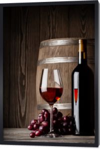 Kieliszek czerwonego wina ze stojącą butelką i beczką