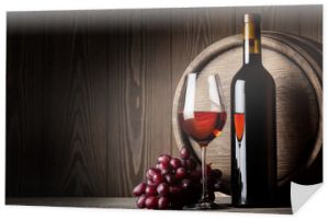 Czarna butelka i kieliszek czerwonego wina z winogronami i beczką