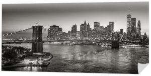 Czarno-biały podniesiony widok na most Brooklyn Bridge i drapacze chmur Dolnego Manhattanu o zmierzchu. Skyline dzielnicy finansowej z East River. Nowy Jork