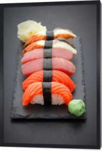 Nigiri sushi ustawione na kamiennej płycie na czarnym tle