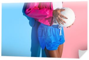 Brzuch młoda dziewczyna trzymając piłkę w ręce na tle różowy i niebieski