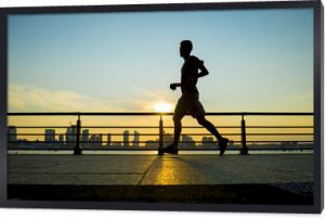 Sylwetka biegacza biegnącego o zachodzie słońca przed panoramą miasta city