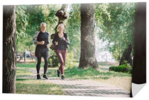 selektywnej ostrości uśmiechniętego dojrzałego sportowca i Sportsmen biegną razem w parku