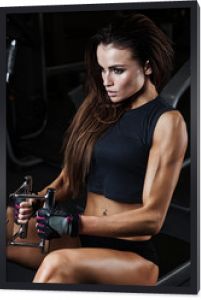 Seksowna brunetka fitness robi ćwiczenia na triceps w sportowej siłowni