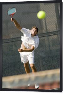 mężczyzna serwujący piłkę tenisową na siatce tenisowej