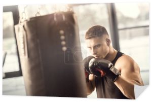 lekkoatletycznego młody człowiek w Rękawice bokserskie, szkolenia z workiem w siłowni