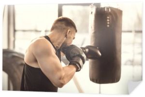 Widok z boku z mięśni młody bokser szkolenia z workiem treningowym