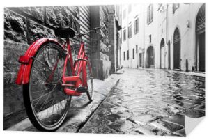 Retro vintage czerwony rower na brukowanej uliczce na starym mieście. Kolor w czerni i bieli