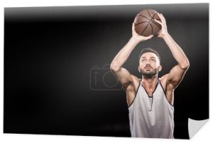 koszykarz mięśni, rzucając piłkę na czarnym tle 