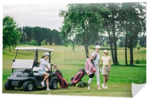 Grupa kobiet graczy w czapki z sprzętu golfowego na polu golfowym w letni dzień