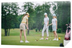 Kobieta w WPR, gry w golfa jednocześnie uśmiechając się przyjaciółmi, stojących w pobliżu pola golfowego