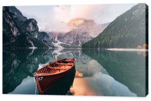 Jesienny czas. Drewniana łódź na krystalicznym jeziorze z majestatyczną górą za. Odbicie w wodzie