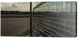 Panoramiczne ujęcie szklanej fasady lotniska z lotniskiem i zachmurzonym niebem w tle w Kopenhadze, Dania 
