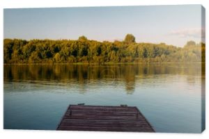 Drewniane molo bez ludzi na spokojnym jeziorze lub rzece. Lato fotografia krajobrazowa