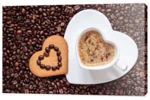 Kubek w kształcie serca i ciastko na tle ziaren kawy