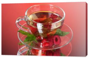 Zielona herbata w przezroczysty kubek z miętą i jagody na czerwonym tle