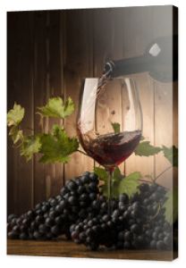 Kieliszek z czerwonym winem i winogronem na drewnianym stole