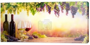 Butelki i kieliszki z winogron o zachodzie słońca