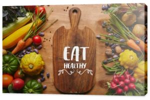 Deska do krojenia z letnich warzyw na drewnianym stole i napis "zdrowe odżywianie"
