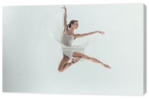 młody eleganckie baleriny w białej sukni skoki w studio, na białym tle