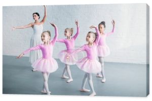 urocze dzieci w różowe tutu spódnice praktykuje balet z młodym nauczycielem w szkole baletowej